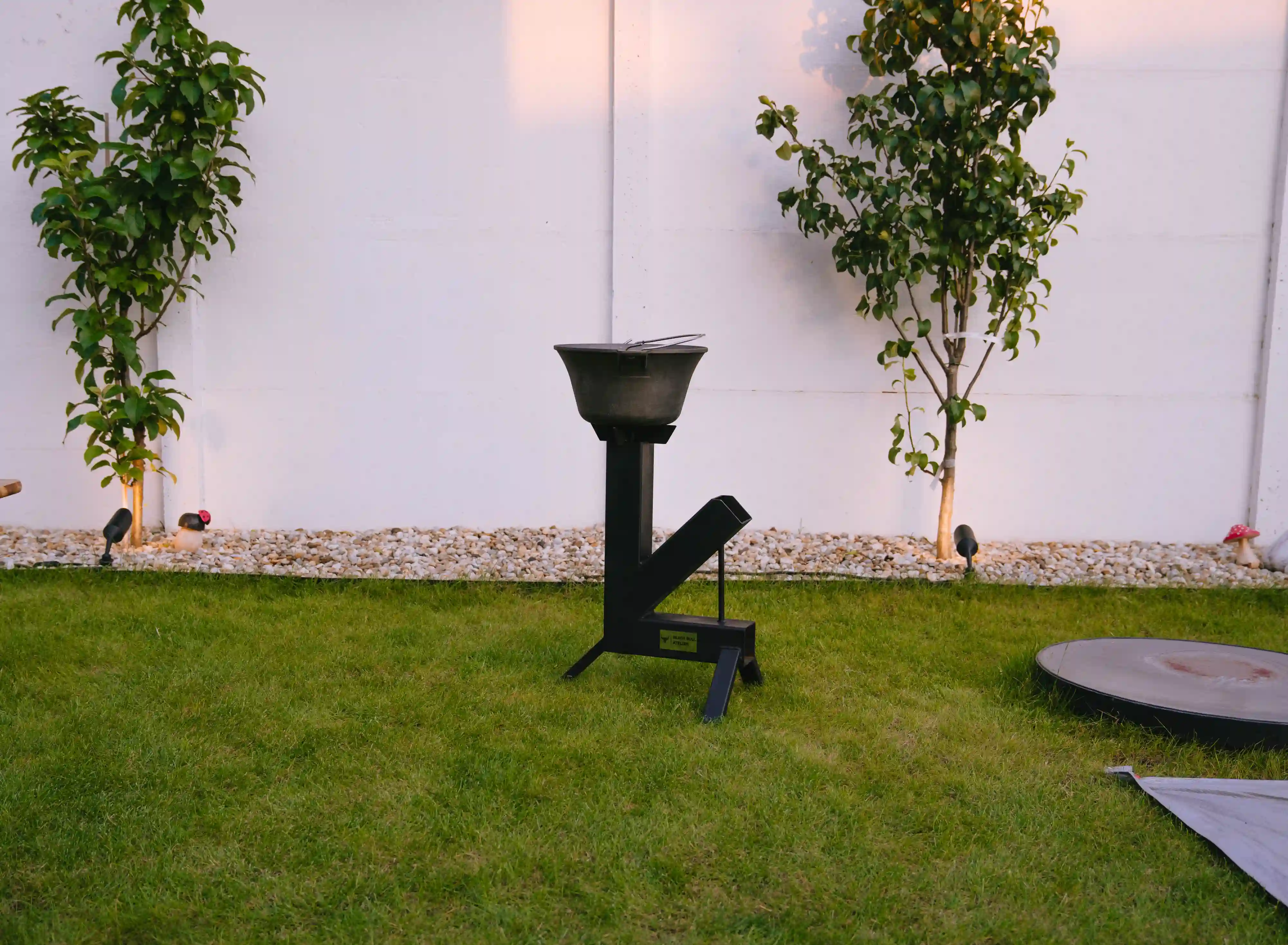 Matt black steel rocket grill, standing in the garden.